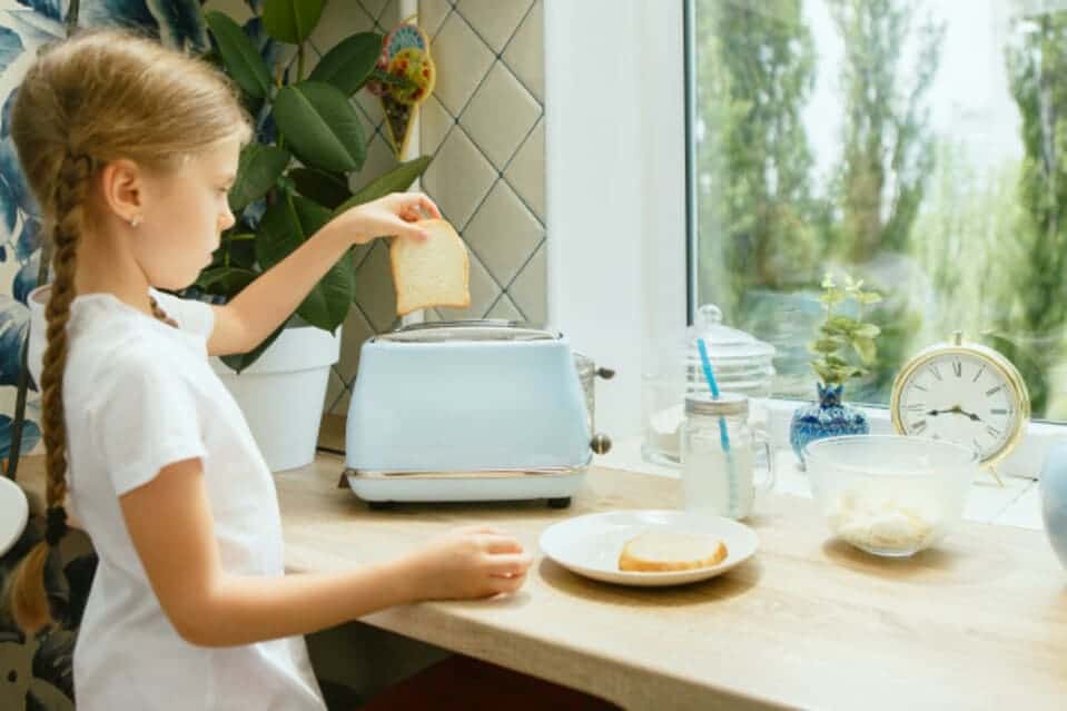 Menina utilizando utensílio doméstico do jeito certo para economizar energia na cozinha