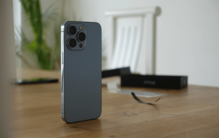 imagem de um iphone azul em pé sobre uma mesa de madeira.